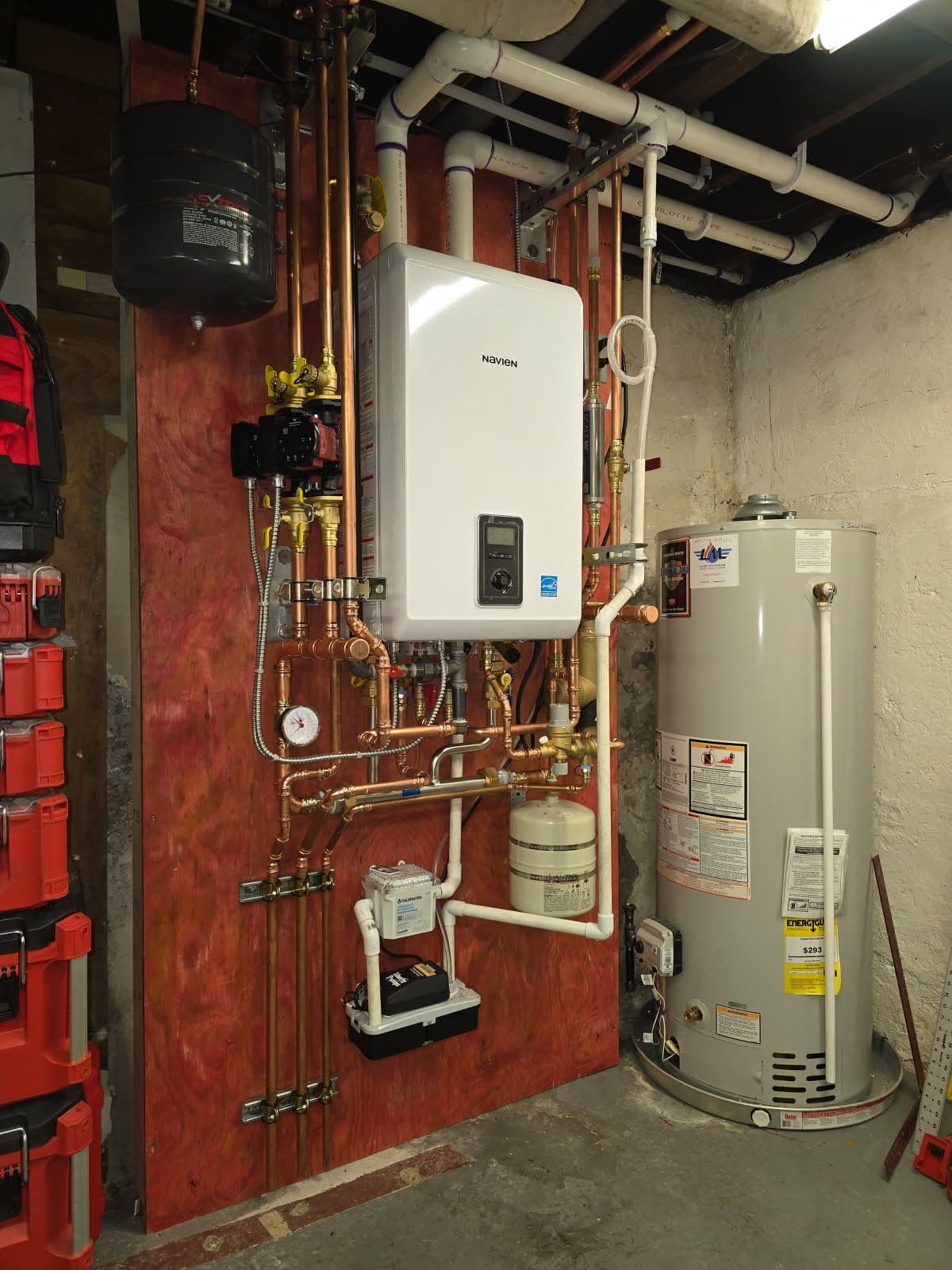 High-efficiency tankless water heater and storage tank in a basement installation.
