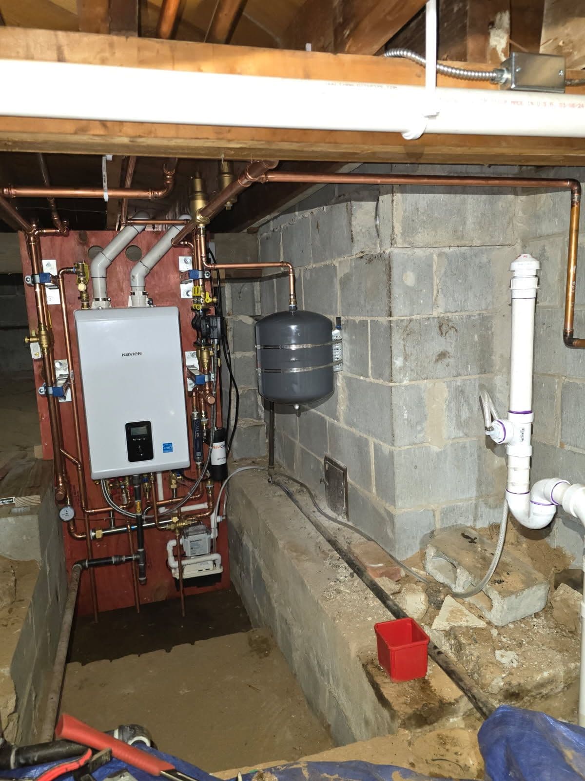 Residential basement plumbing with water heater, pipes, and gray water tank installation.